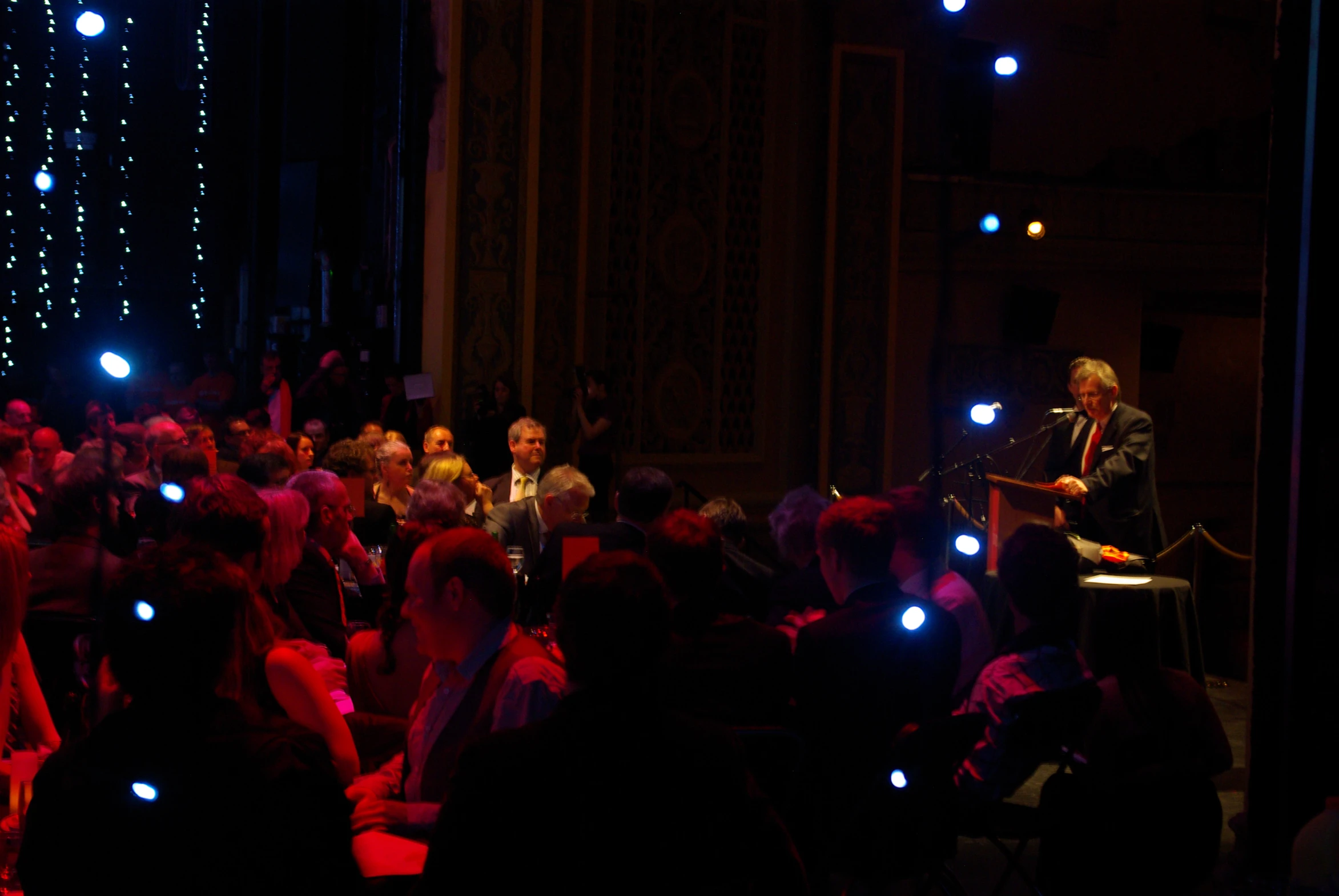 a person in a crowd standing up talking into a microphone