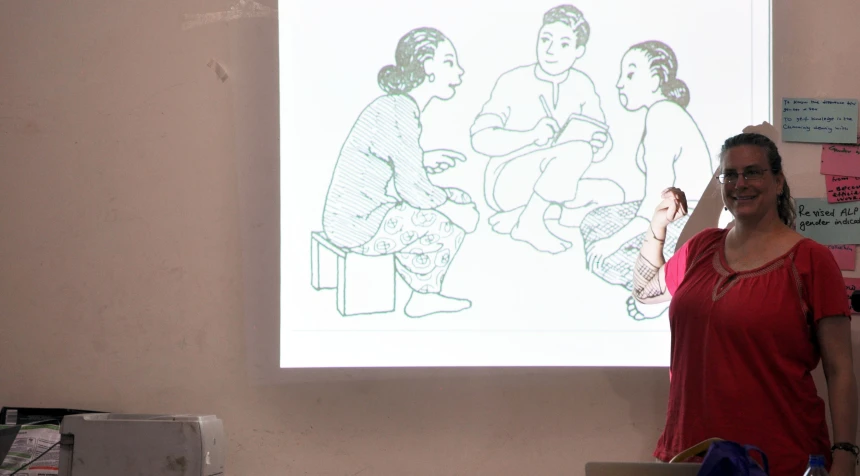 a woman in a red shirt stands in front of a presentation on the screen