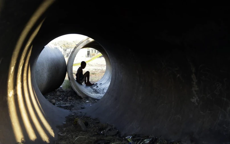 a man in a tunnel sits alone while looking through the hole