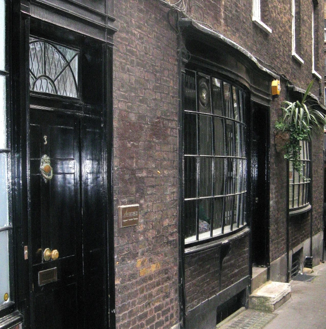 two dark brown buildings are on the side of a sidewalk