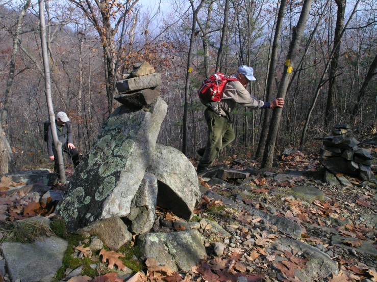 two people are climbing up on rocks in the woods