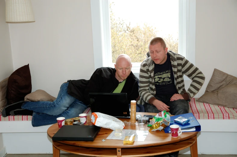 two men sitting down looking at a laptop computer