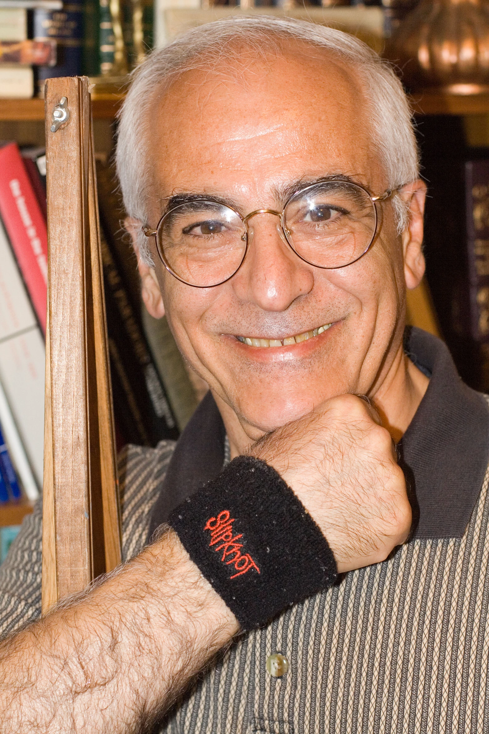 an elderly man with glasses and a arm band smiling