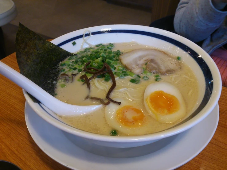 a white bowl filled with soup with an egg and broth