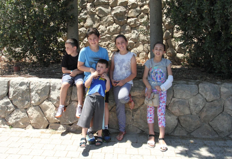 several young s sitting together on a wall