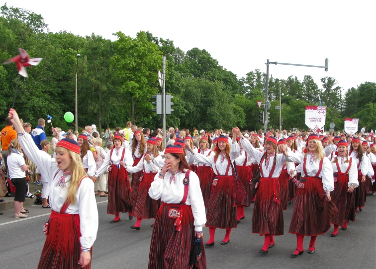 a large group of women in colorful dresses and hats walking in a parade