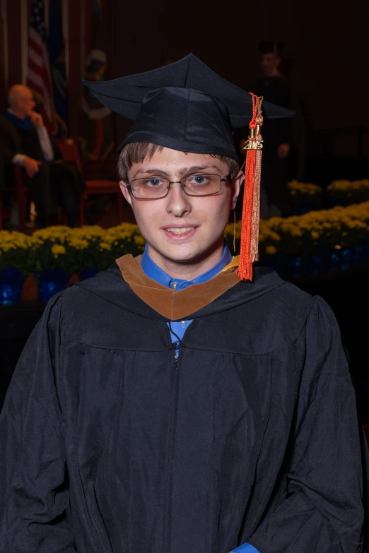 the young male student is dressed in his graduation gown and cap