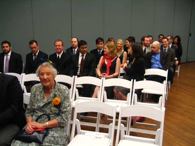 a group of people wearing suits are standing near a row of chairs