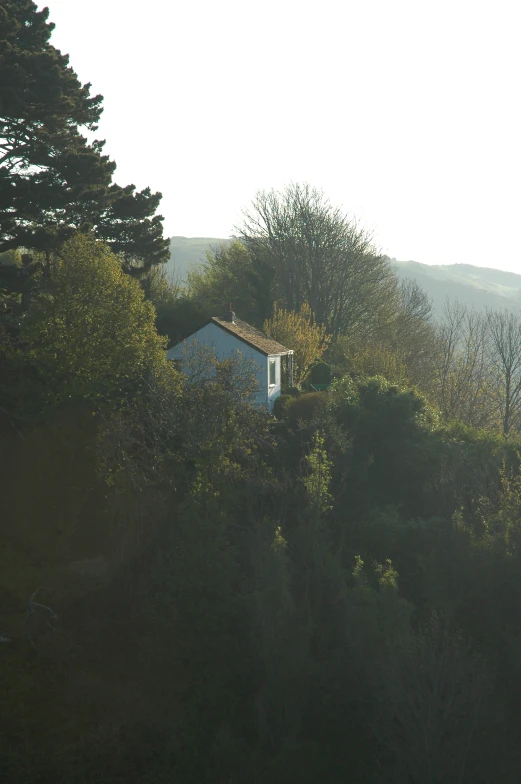 a house sits on top of the hill by some trees