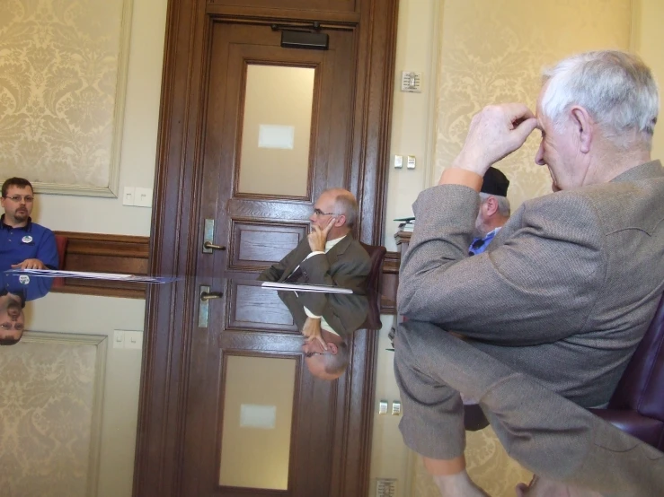 a man holding a pair of glasses over his eyes in front of the people waiting