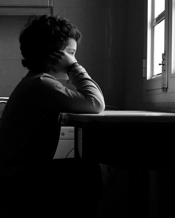 a person sitting at a table in front of a window