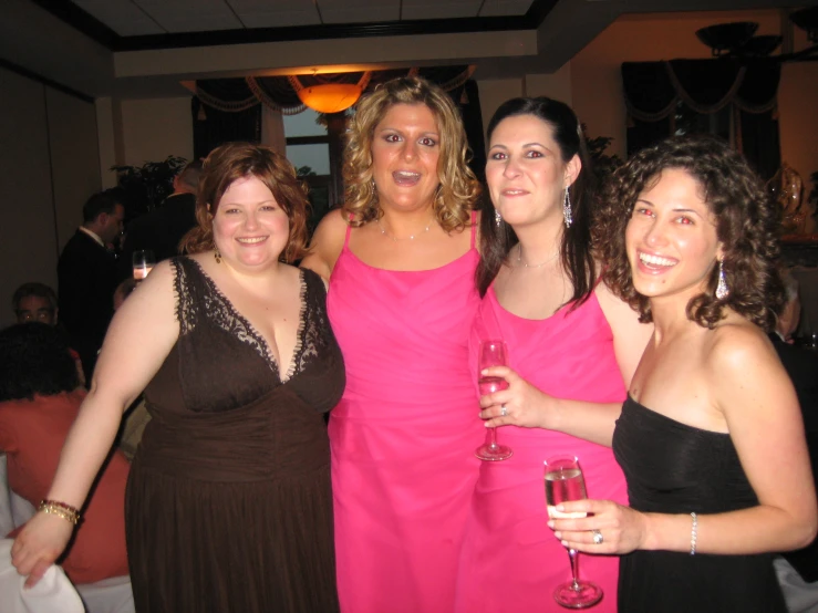 three women in formal dress posing with wine glasses