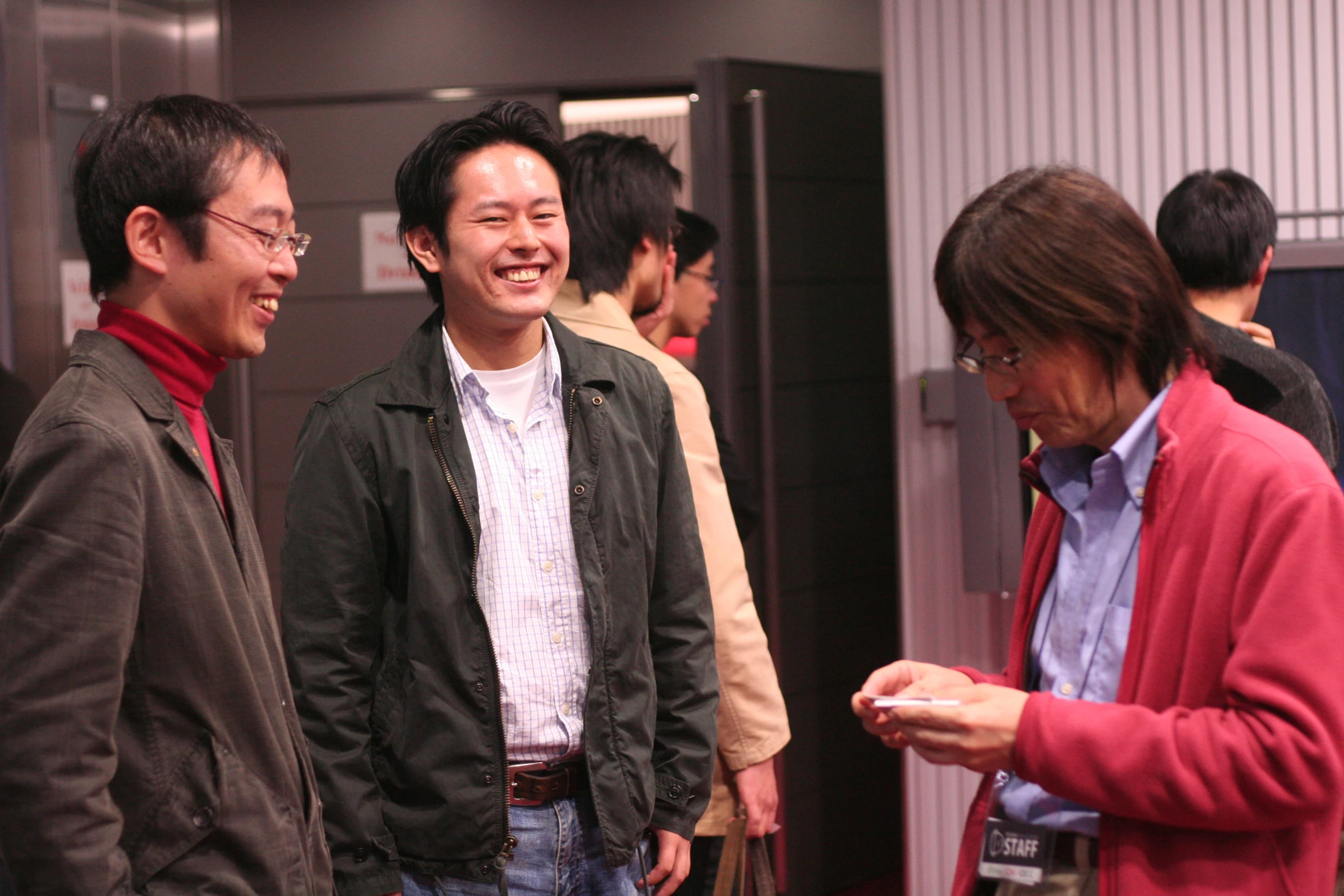 people in an elevator stand looking at a phone