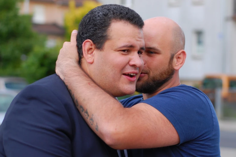 two men hug each other while standing on a city street