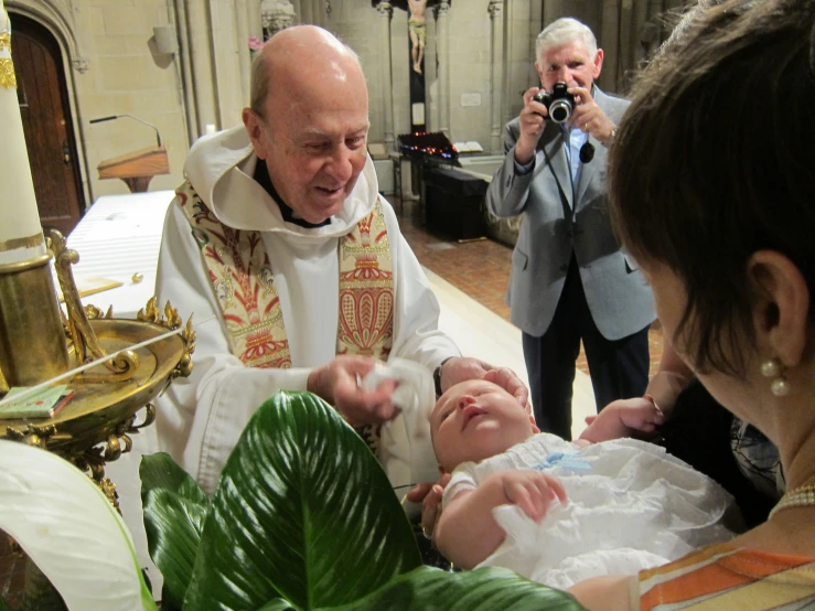 an older man standing next to another priest