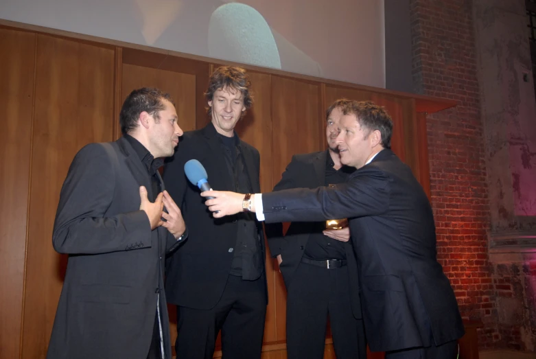 three men dressed in suit talk to each other