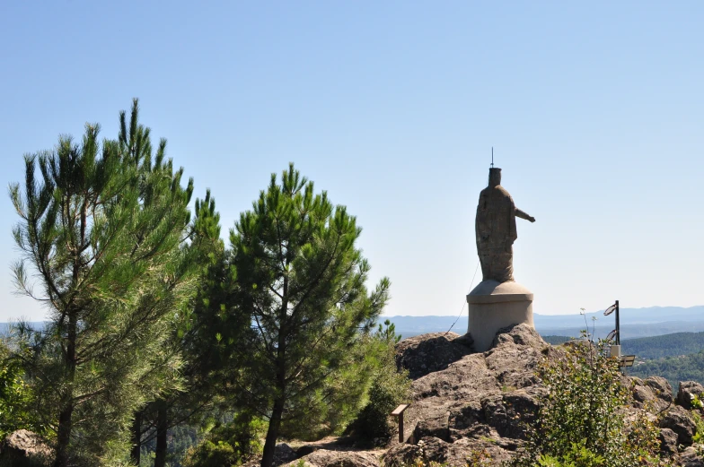 a statue of a man holding a sword on top of a hill