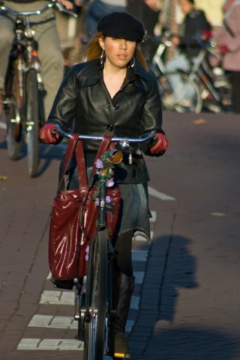 a woman in a black leather jacket riding a bike