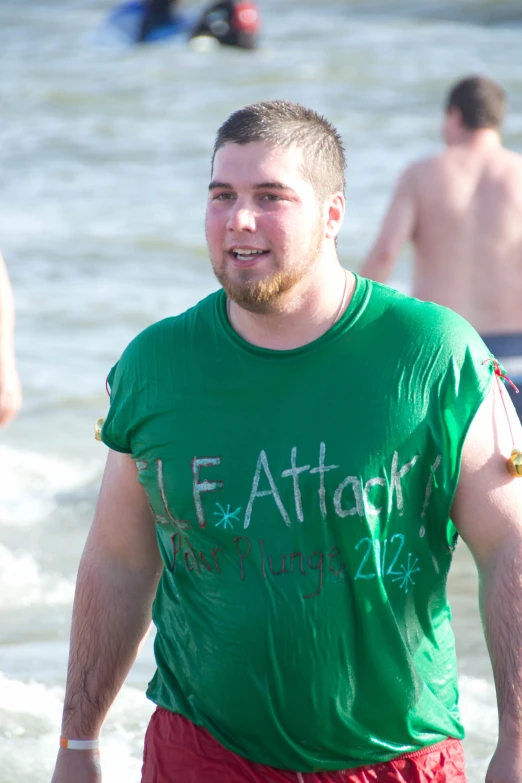 the young man wearing a green shirt is walking in the water