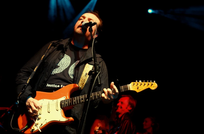 a man on stage holding an electric guitar and singing