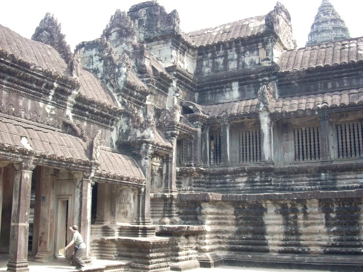 a woman in a grey top walking through an ancient stone structure