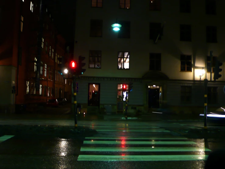 a wet city street at night with a red stop light