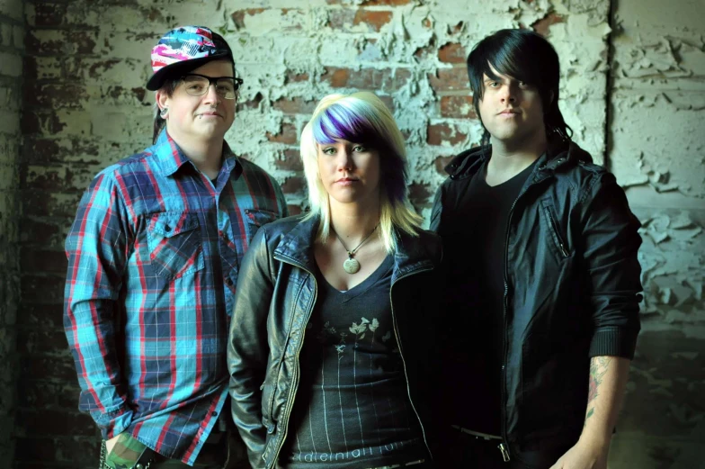 three people are posing for a po in front of a brick wall