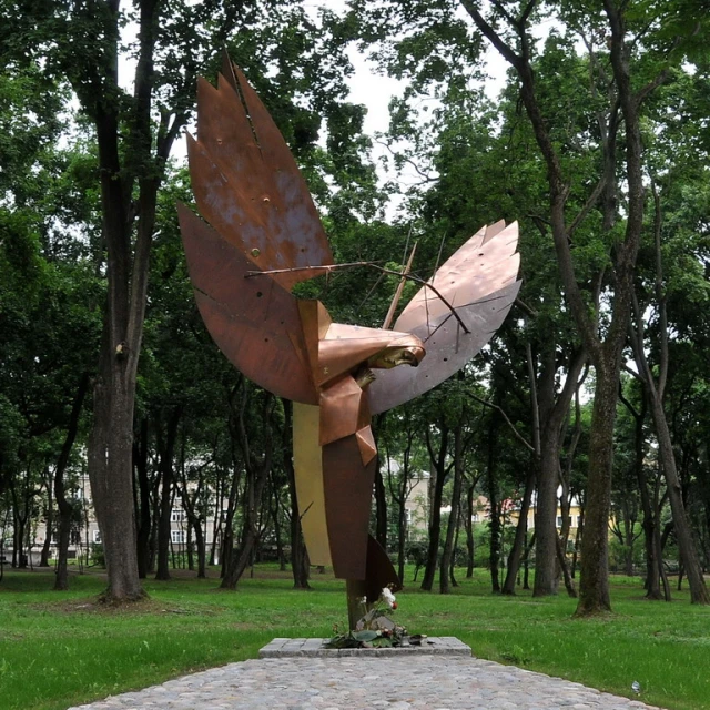 a large bird statue in front of trees