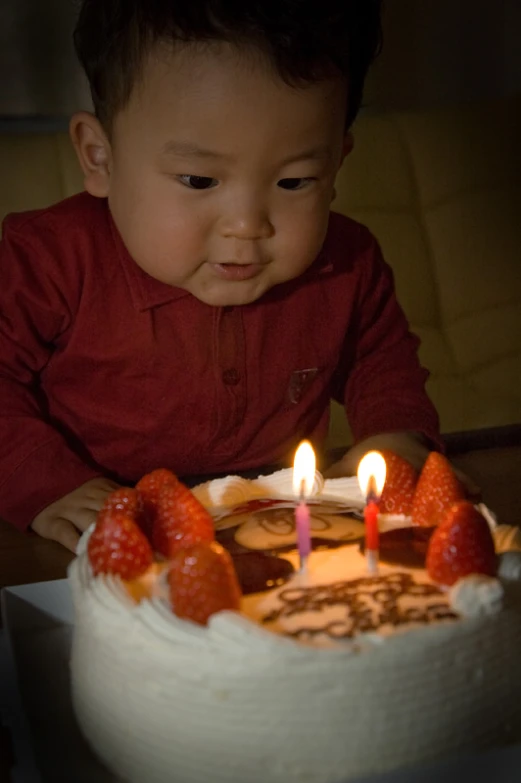 a baby sitting in front of a cake with candles