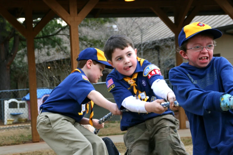 three boys playing with each other in a park