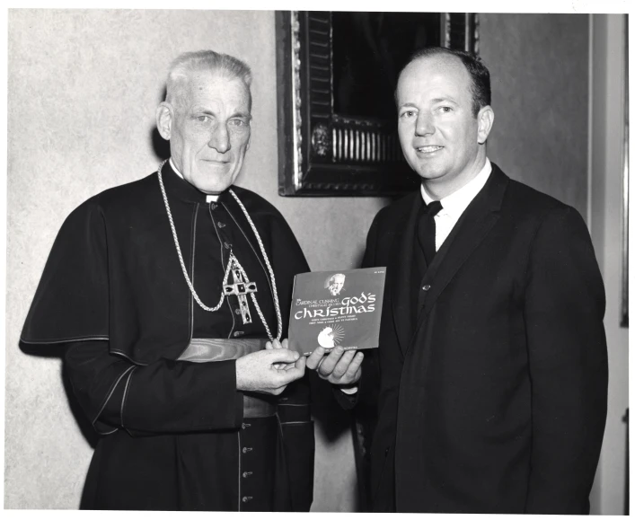 priest giving a plaque to a man in his black robes