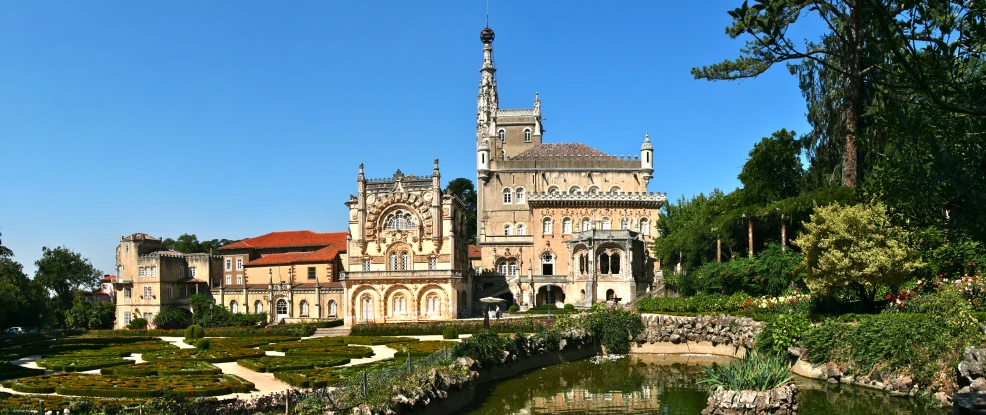 a building with a tall tower sits at the edge of a garden