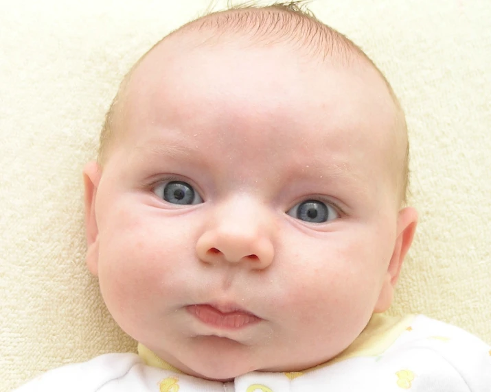 a very young baby with a white shirt and blue eyes