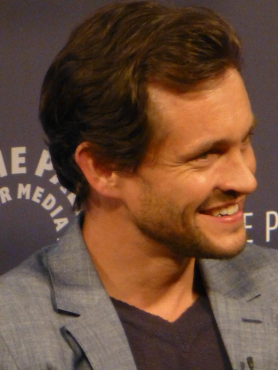 a man in a gray jacket smiling at soing