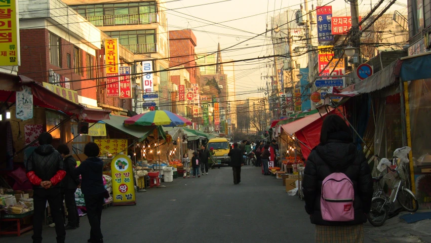 people are walking down the street in a small market