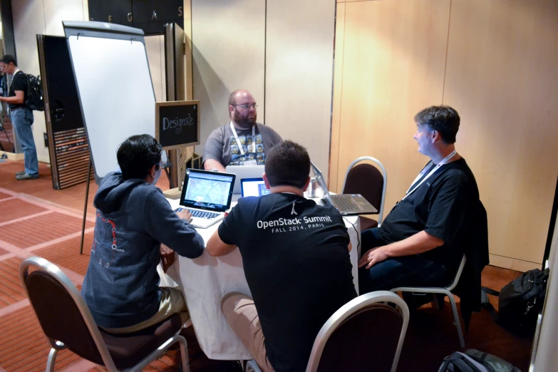 men sitting at a round table looking at computers