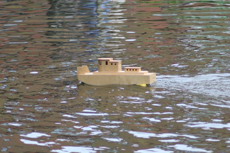 a wooden toy boat floating on a lake filled with water