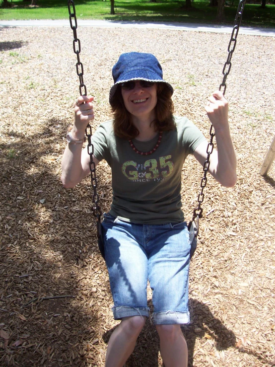 a smiling woman sitting on a rope swing