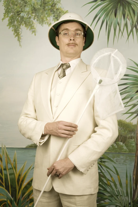 a man with a suit and hat holding a plastic fan