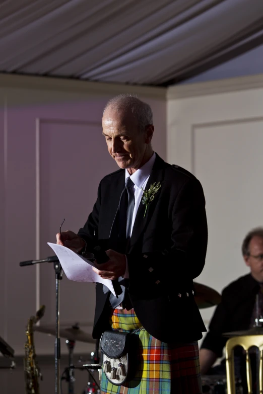 a man in a kilt stands in front of a microphone