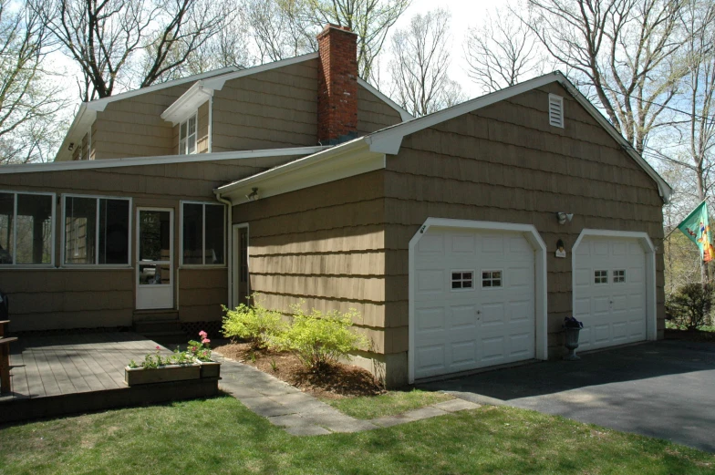 a picture of a brown house with two garages and two open windows