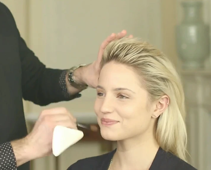 a woman getting her hair styled by a man