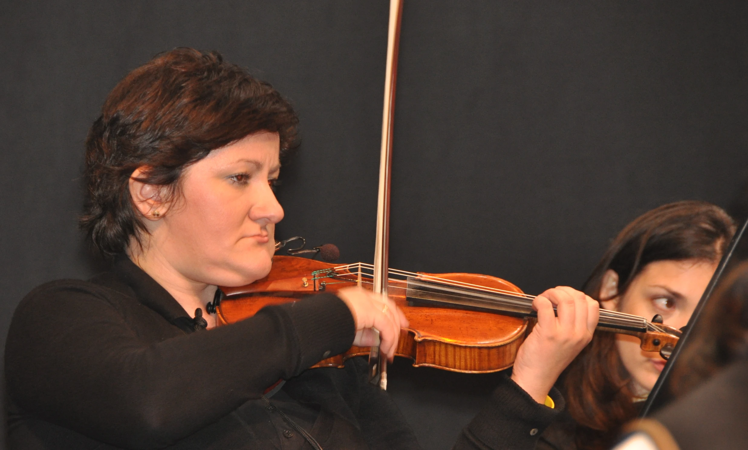 a woman holding onto the strings of a violin