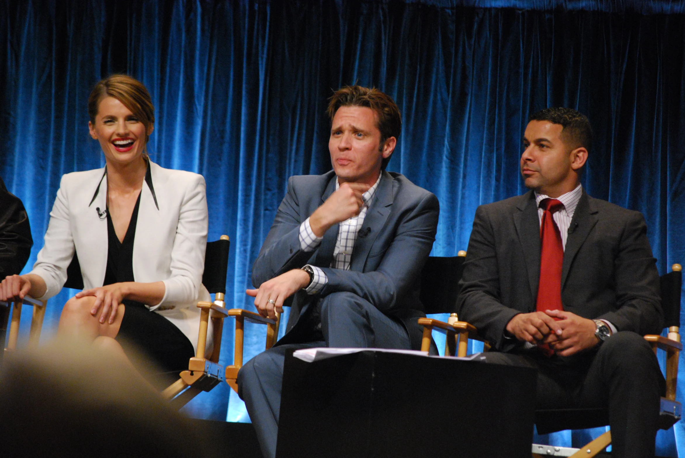 four people in suits are sitting on stage