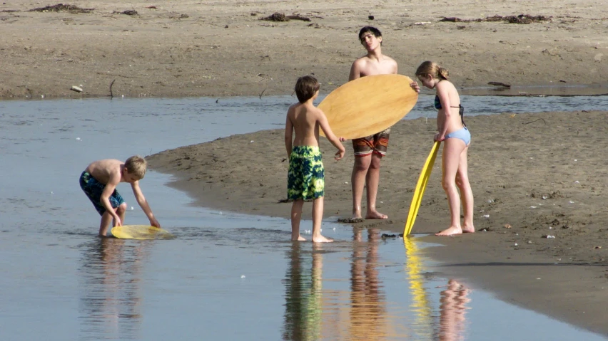 four s playing with a yellow frisbee on the beach