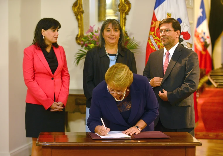 a woman in blue dress signing a document with a man