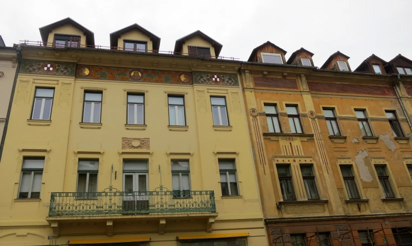 buildings with some windows and a balcony and a car parked outside