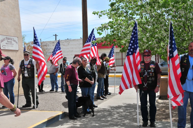 people standing on the sidewalk, many holding flags