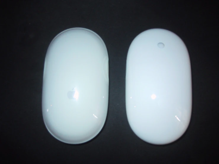 two white computer mouses sit on a table