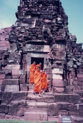 two monks wearing orange robes walk up some steps